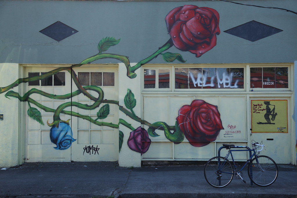 A mural showing a painting of a red rose with a bicycle parked in front of it at Alberta's Art District, Portland, Oregon.